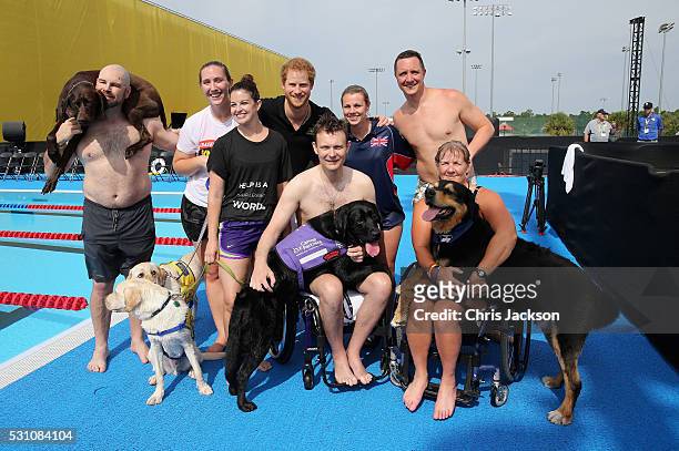 Prince Harry poses with Service Dogs and their Invictus competitor handlers after a race in the pool on the final day of the Invictus Games Orlando...