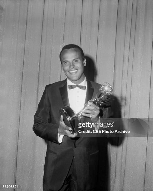 American actor, singer, and composer Harry Belafonte poses in front of a glittery curtain with the Emmy statue that he had just won for his CBS...