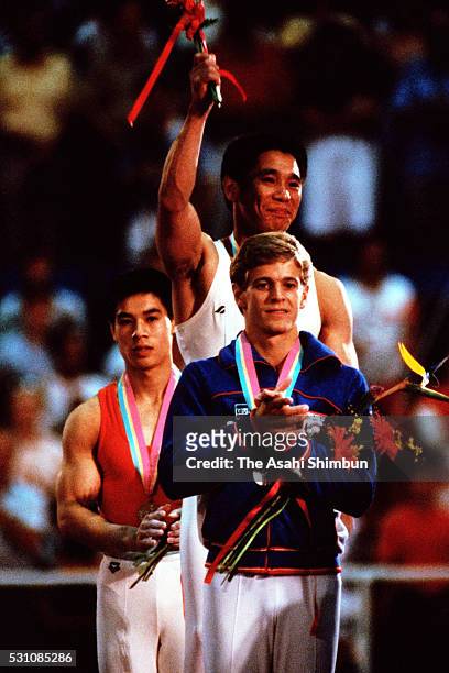 Bronze medalist Li Ning of China, gold medalist Koji Gushiken of Japan and silver medalist Peter Vidmar of the United States pose on the podium at...