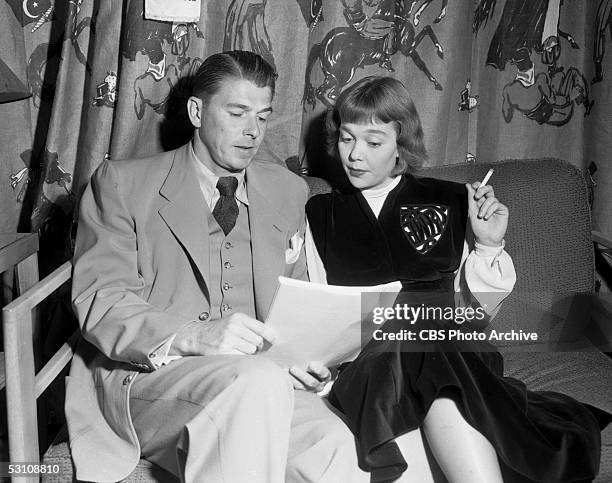 American actor and President Ronald Reagan and his wife, American actress Jane Wyman sit on a couch in a green room and read their lines from a...