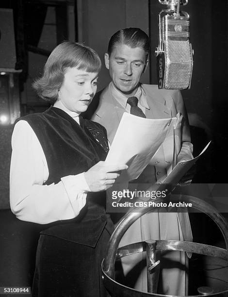 American actor and President Ronald Reagan and his wife, American actress Jane Wyman read from scripts and speak into a hanging microphone in a radio...