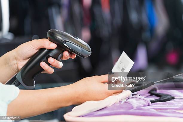 hands using scanner to scan price tag in clothing store - barcodelezer stockfoto's en -beelden