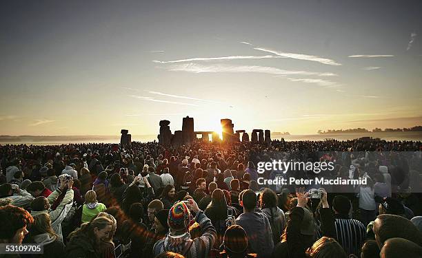 People watch the midsummer sun as it rises over the megalithic monument of Stonehenge on June 21, 2005 on Salisbury Plain, England. Crowds gathered...