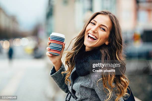 young woman with coffee cup smiling outdoors - beautiful smile stock pictures, royalty-free photos & images