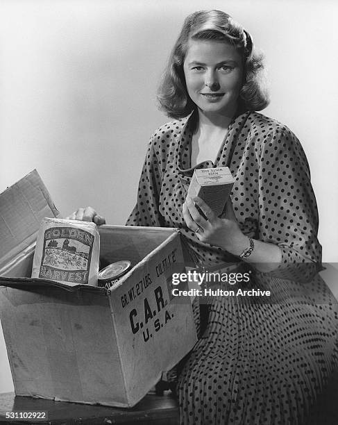 Portrait of Swedish actress Ingrid Bergman as she poses with a CARE package, 1940s or 1950s. CARE was a humanitarian agency, its acronym later...