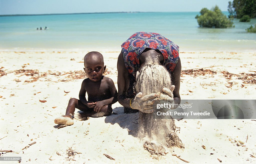 Australia - Arnhem Land - Northern Territory - Aboriginal woman cleans her hair in the sand