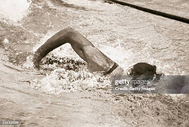 American swimmer Johnny Weissmuller takes a breath while swimming freestyle. Johnny Weissmuller won three swimming golds and a bronze playing water...