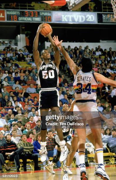 David Robinson of the San Antonio Spurs goes for the jump shot against Danny Schayes of the Denver Nuggets during the game circa 1989 -1990 at the...