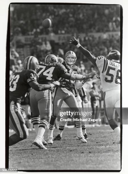 Quarterback Joe Montana of the San Francisco 49ers throws a pass as he is rushed by Chris Doleman of the Minnesota Vikings during the 1989 NFC...