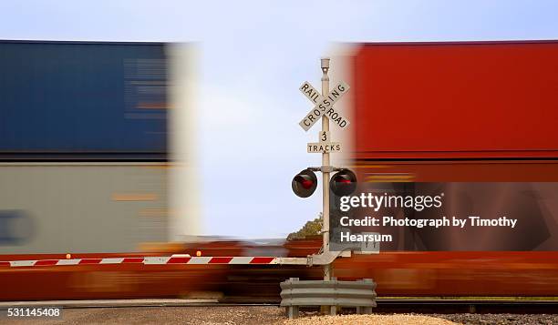 close up view of colorful train cars speeding through an intersection - 貨物列車 ストックフォトと画像