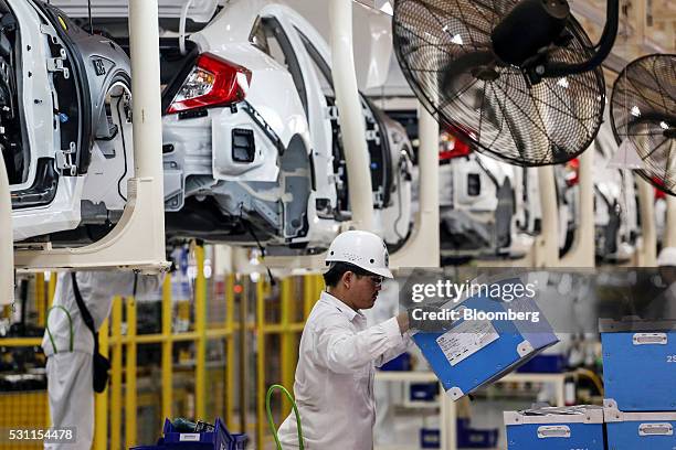 An employees lifts a box while working Honda Civic vehicles on the production line of the Honda Motor Co. Assembly plant in Prachinburi, Prachinburi...