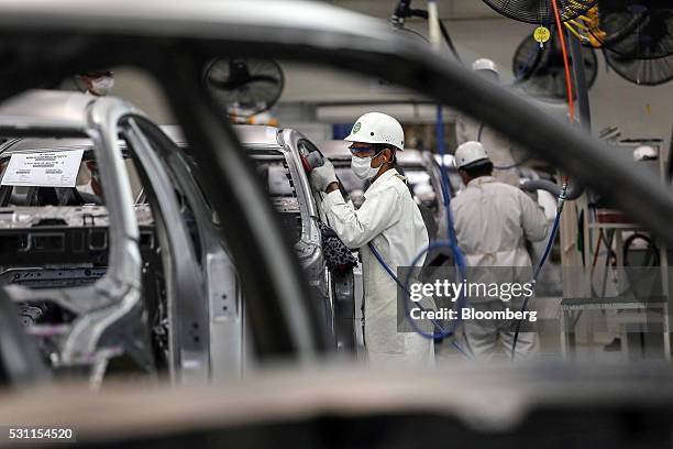 Employees grind and buff welds on the frame of a Honda Civic vehicle on the production line of the Honda Motor Co. Assembly plant in Prachinburi,...