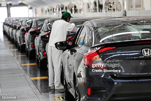 An employee checks a Honda Civic vehicle at the quality control station on the production line of the Honda Motor Co. Assembly plant in Prachinburi,...