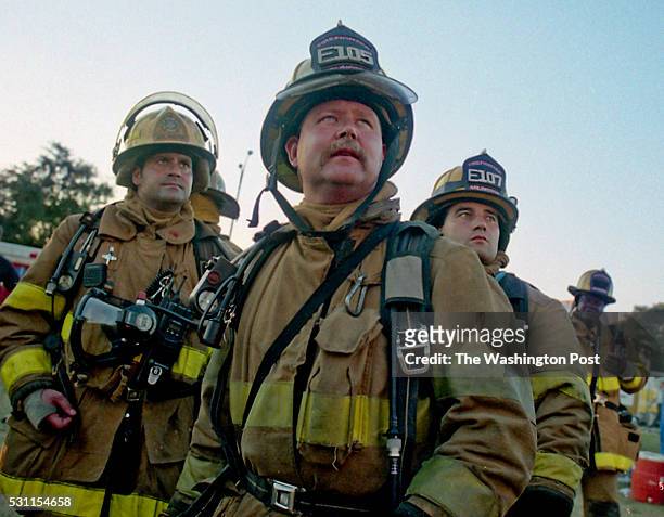 Firefighters from Arlington County, Virginia look up at the Pentagon before they enter as flames reappear from the upper floors, in Arlington, VA on...