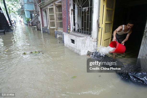 Resident scoops water from his flooded house at Shamian Island on June 22, 2005 in Guangzhou of Guangdong Province, southern China. Streets in...