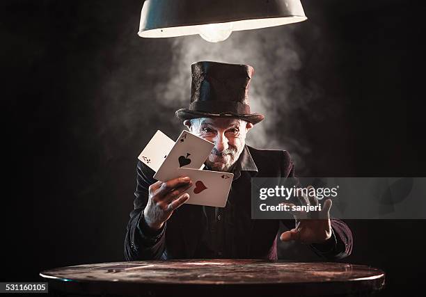 alter mann, trick mit spielkarten - zauberer darstellender künstler stock-fotos und bilder