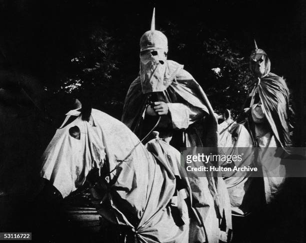 Actors costumed in the full regalia of the Ku Klux Klan ride on horses at night in a still from 'The Birth of a Nation,' the first-ever...