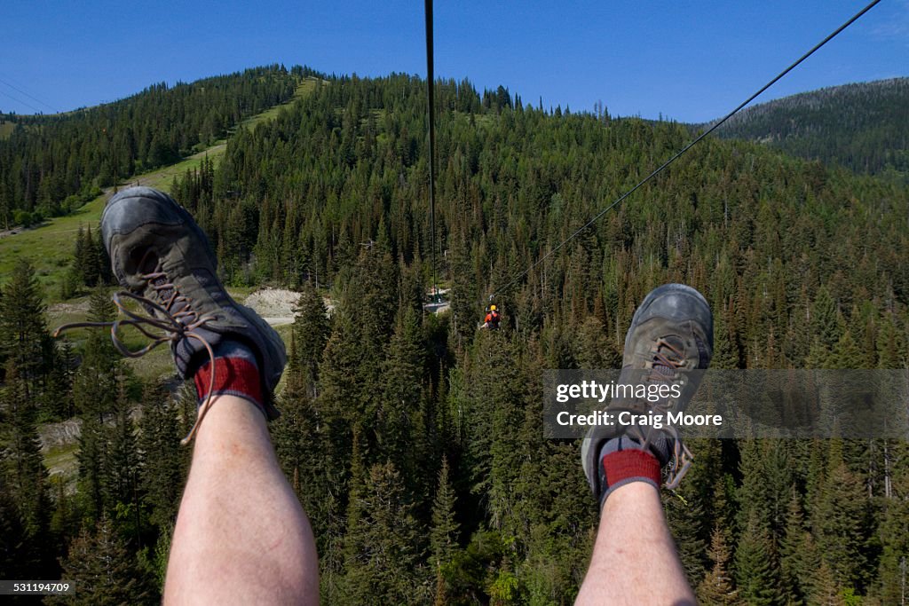 Two men ride a zip line at Whitefish, Montana.