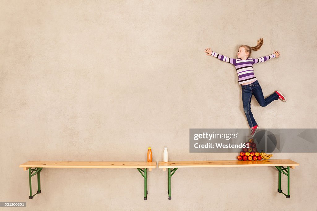 Girl balancing on pile of apples