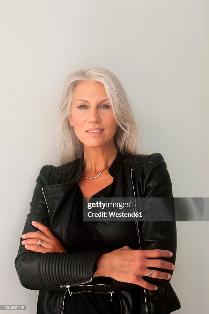 Portrait of mature woman with crossed arms leaning at a wall