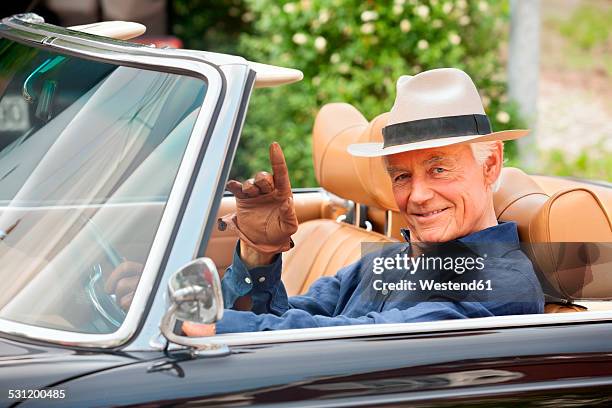 portrait of a smiling senior sitting in a convertible car waving - old car bildbanksfoton och bilder