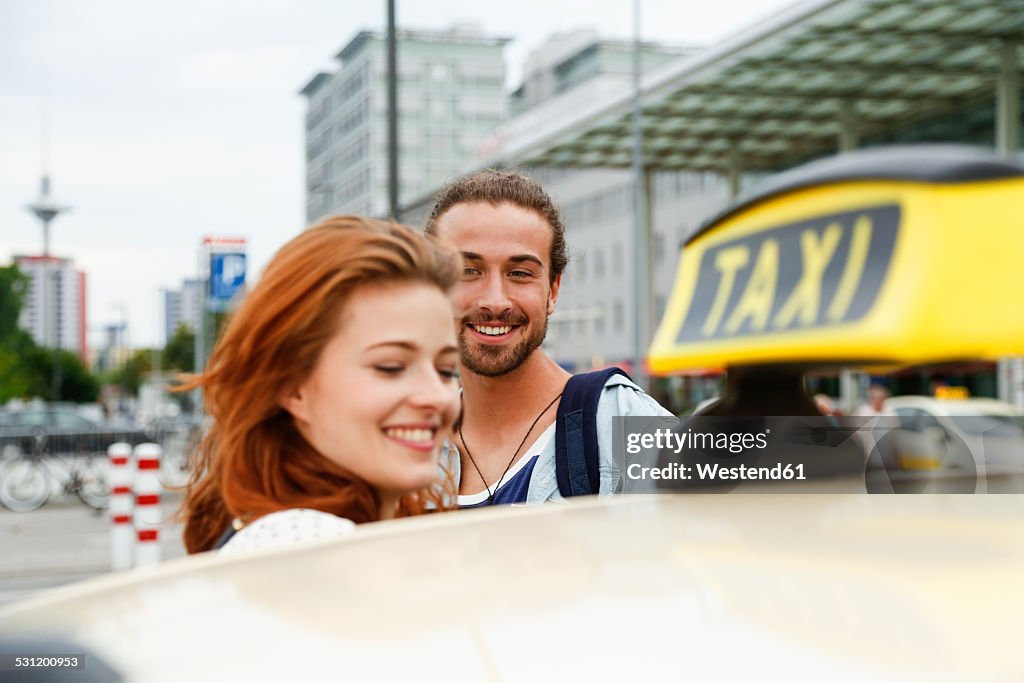 Germany, Berlin, Young couple taking taxi