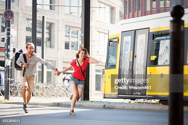 germany, berlin, young couple running in street - urgency stock pictures, royalty-free photos & images