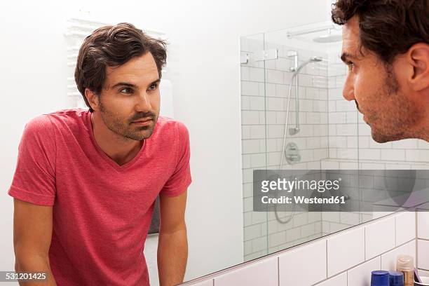 mirror image of young man watching himself - barba por fazer imagens e fotografias de stock