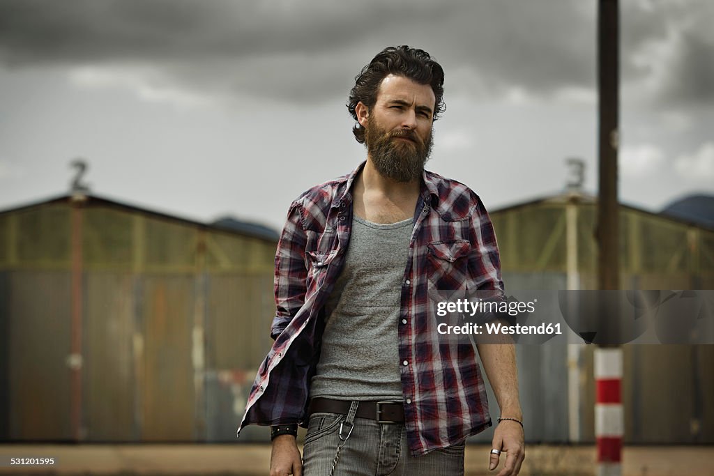 Serious man with full beard in abandoned landscape