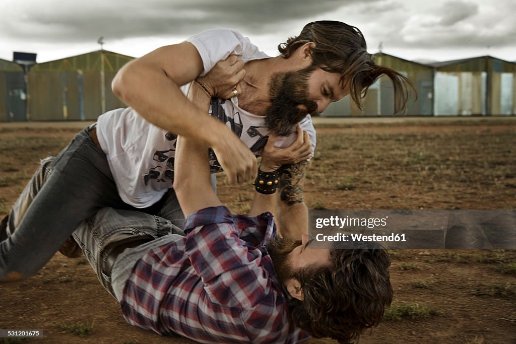 Wo men with full beards fighting in abandoned landscape