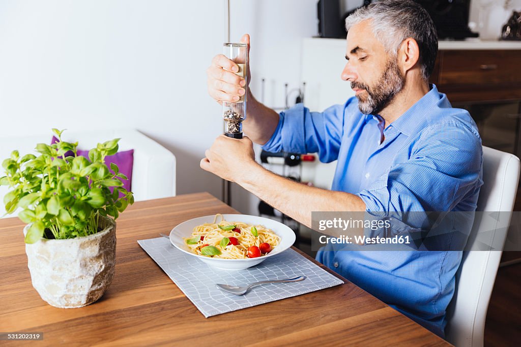 Man flavouring his pasta with pepper