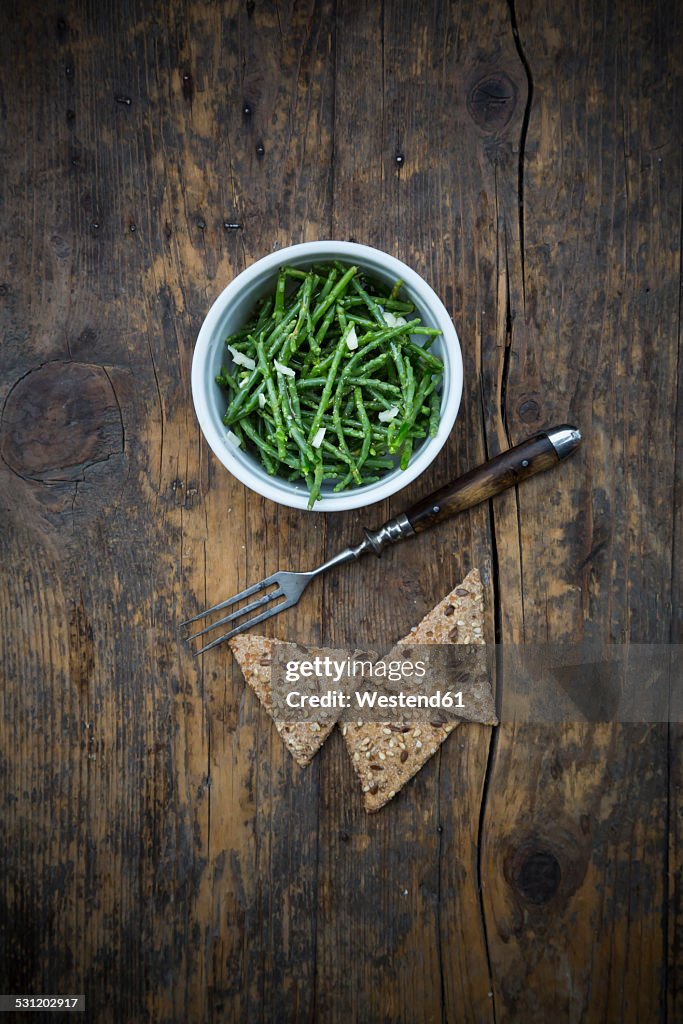 Bowl of saltwort salad and rye crackers on dark wood