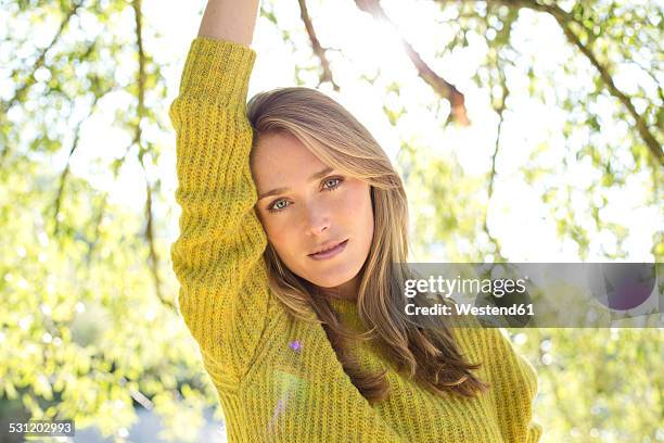 portrait of young woman wearing knit pullover - blond hair young woman sunshine stock pictures, royalty-free photos & images