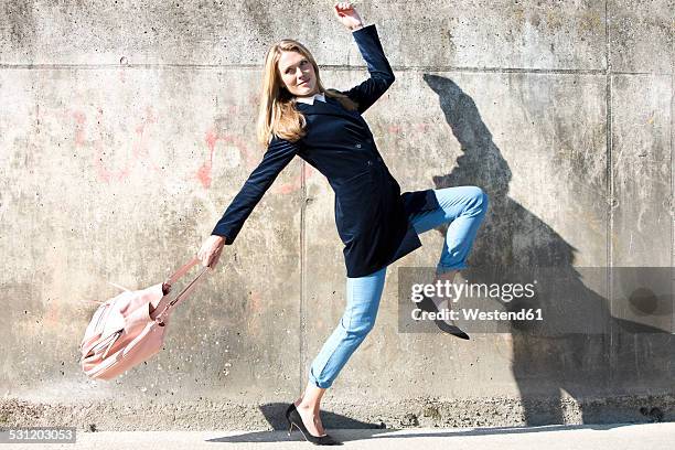 young woman wearing velvet blazer posing in front of a wall - pump schoen stock-fotos und bilder