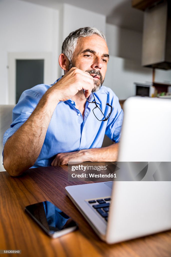 Pensive businessman working with laptop at home office