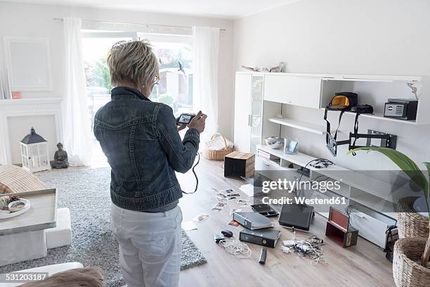 woman photographing chaos after burglary when coming back in her one-family house - coming back stock pictures, royalty-free photos & images