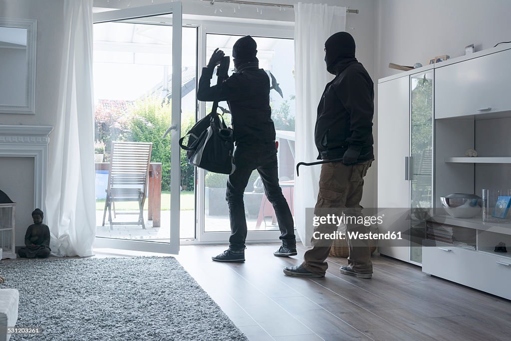 Two burglars leaving an one-family house with their loot at daytime