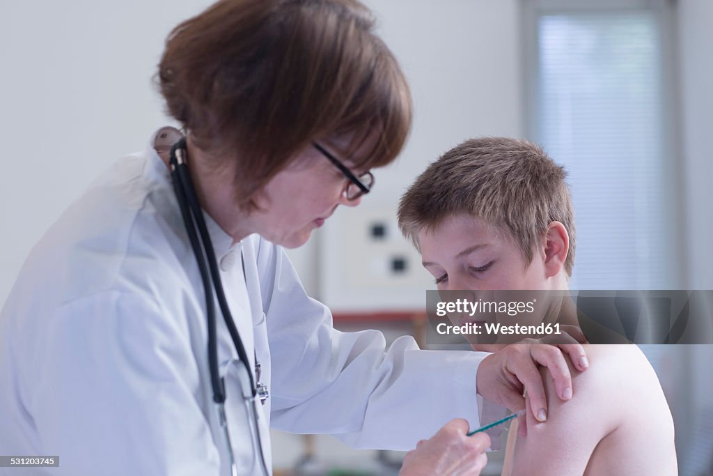 Doctor giving boy an injection in medical practice
