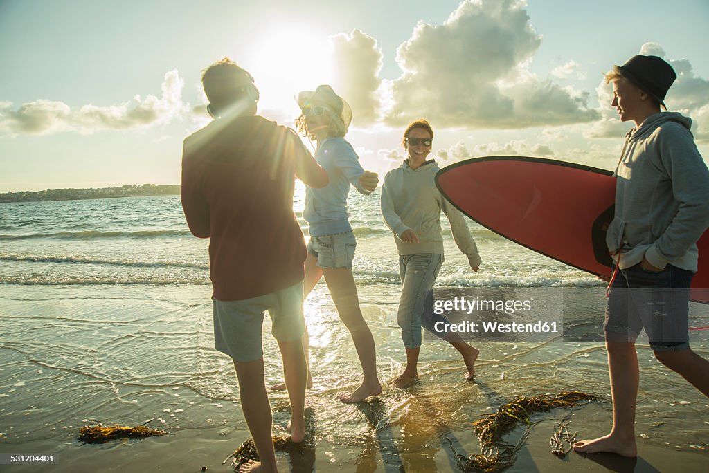 Woman and three teenagers walking at waterside of the sea