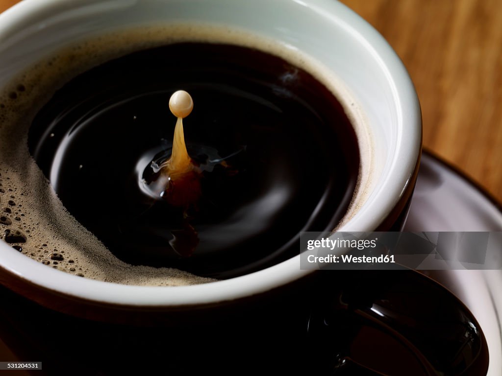 Drop of milk in cup of coffee