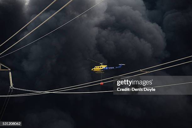 Helicopter drops water onto burning tyres at an illegal dump on May 13, 2016 in Sesena Nuevo, Spain. The dump, which stored over 75.000 tonnes of...