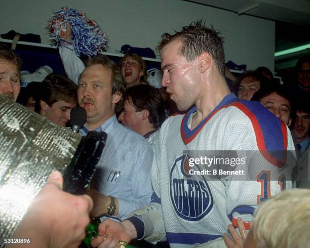 Mark Messier of the Edmonton Oilers walks towards the Stanley Cup Trophy while celebrating in the locker room after the Oilers defeated the New York...