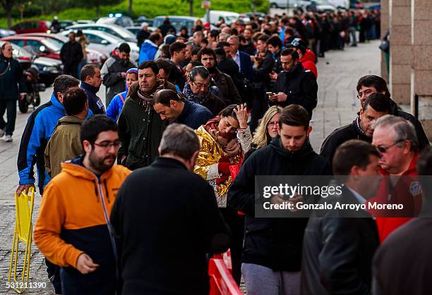 An Atletico de Madrid fan covered with a foil blanket reacts as she queues up to purchase a ticket for the UEFA Champions League Final between Club...