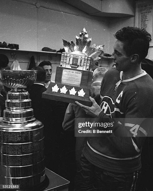 Jean Beliveau of the Montreal Canadiens holds the Conn Smythe Trophy in the locker room after defeating the Chicago Blackhawks in Game 7 of the 1965...