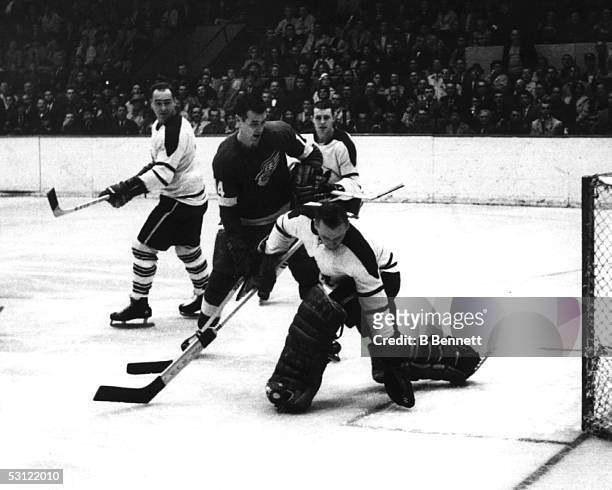 Goalie Johnny Bower of the Toronto Maple Leafs makes the save on Ed Litzenberger of the Detroit Red Wings on November 6, 1961 at Detroit Olympia...