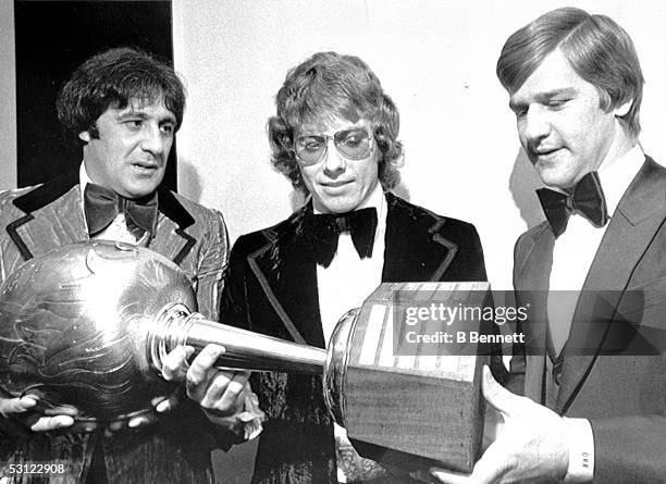 Bobby Clarke of the Philadelphia Flyers shows his Hart Trophy to former winners Phil Esposito and Bobby Orr of the Boston Bruins on November 19, 1973...