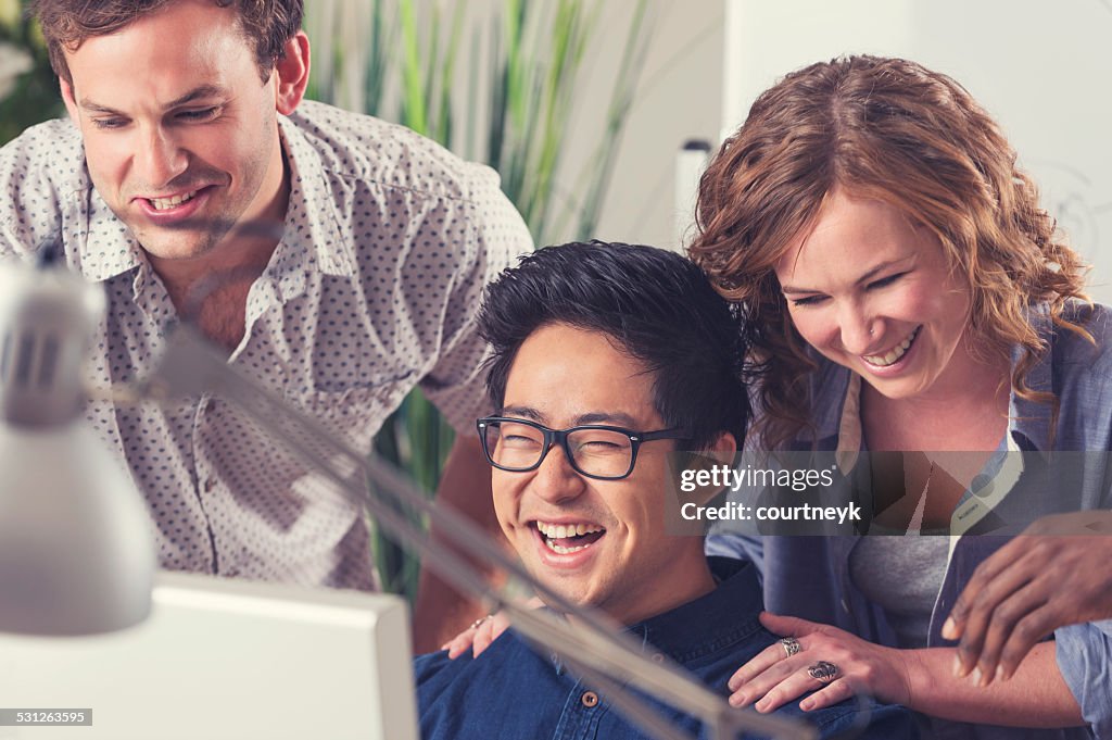 Business team enjoying themselves while looking at a computer.