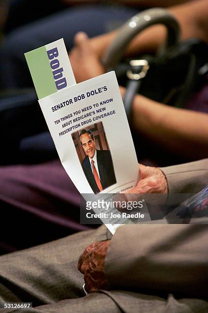 Senior citizen holds a pamphlet as he listens to former U.S. Senator Bob Dole speak during a news briefing to kick off a nationwide speaking tour...