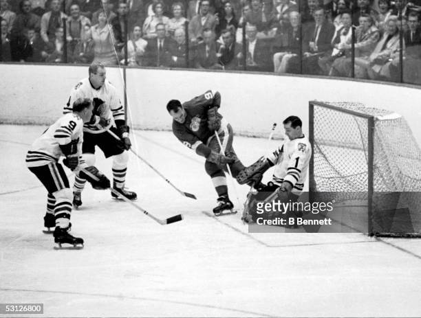 Gordie Howe of the Detroit Red Wings has his shot blocked by goalie Glenn Hall of the Chicago Blackhawks as Bobby Hull and Elmer "Moose" Vasko of the...