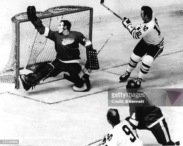 Goalie Roy Edwards of the Detroit Red Wings makes a save on Dennis Hull of the Chicago Black Hawks as Bobby Hull looks for the rebound during their...